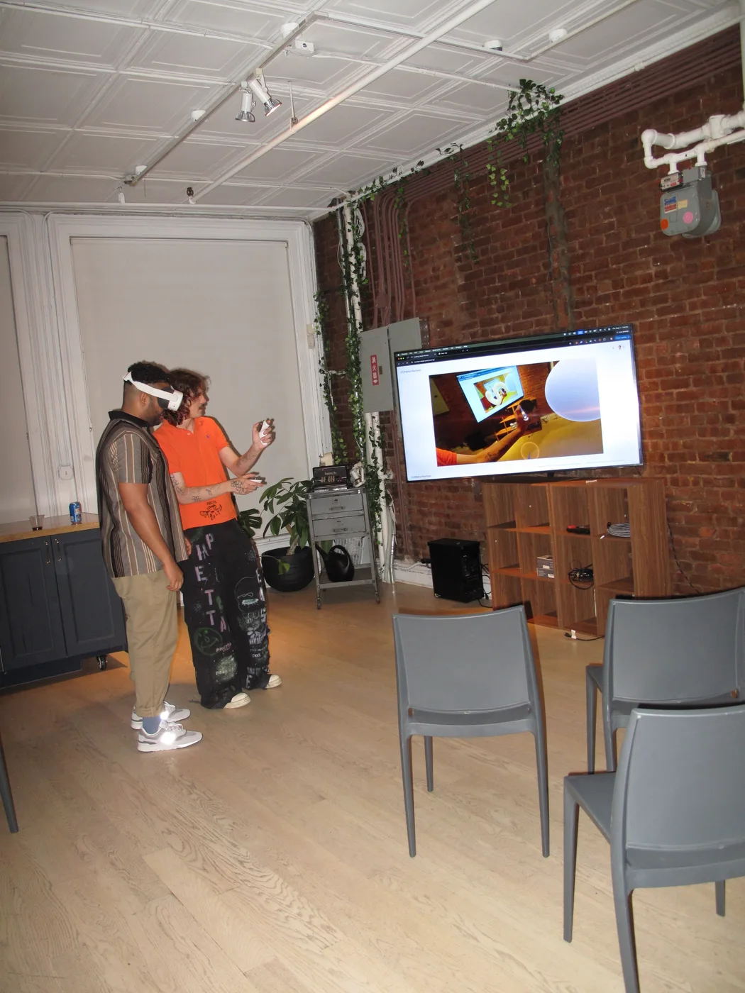A wide view of the gallery with a VR participant and the experience displayed on a screen